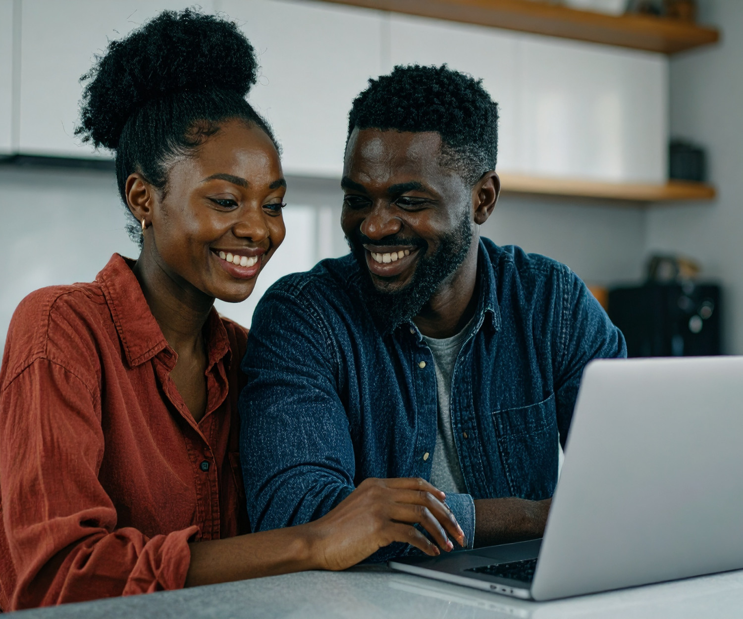 Smiling couple celebrating bond approval in south africa at home with a laptop and documents.